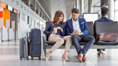 A happy couple sit together at an airport