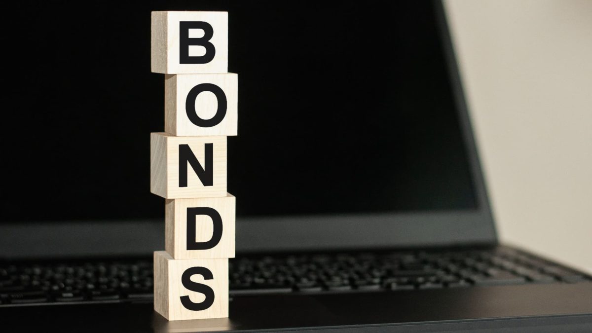 Bonds spelt out on block cubes stacked on top of each other in front of a laptop.