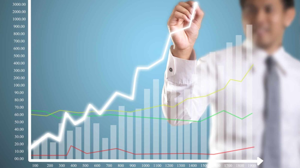 Man drawing an upward line on a bar graph symbolising a rising share price.