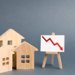 Red arrow on a stand going down with wooden houses next to it.