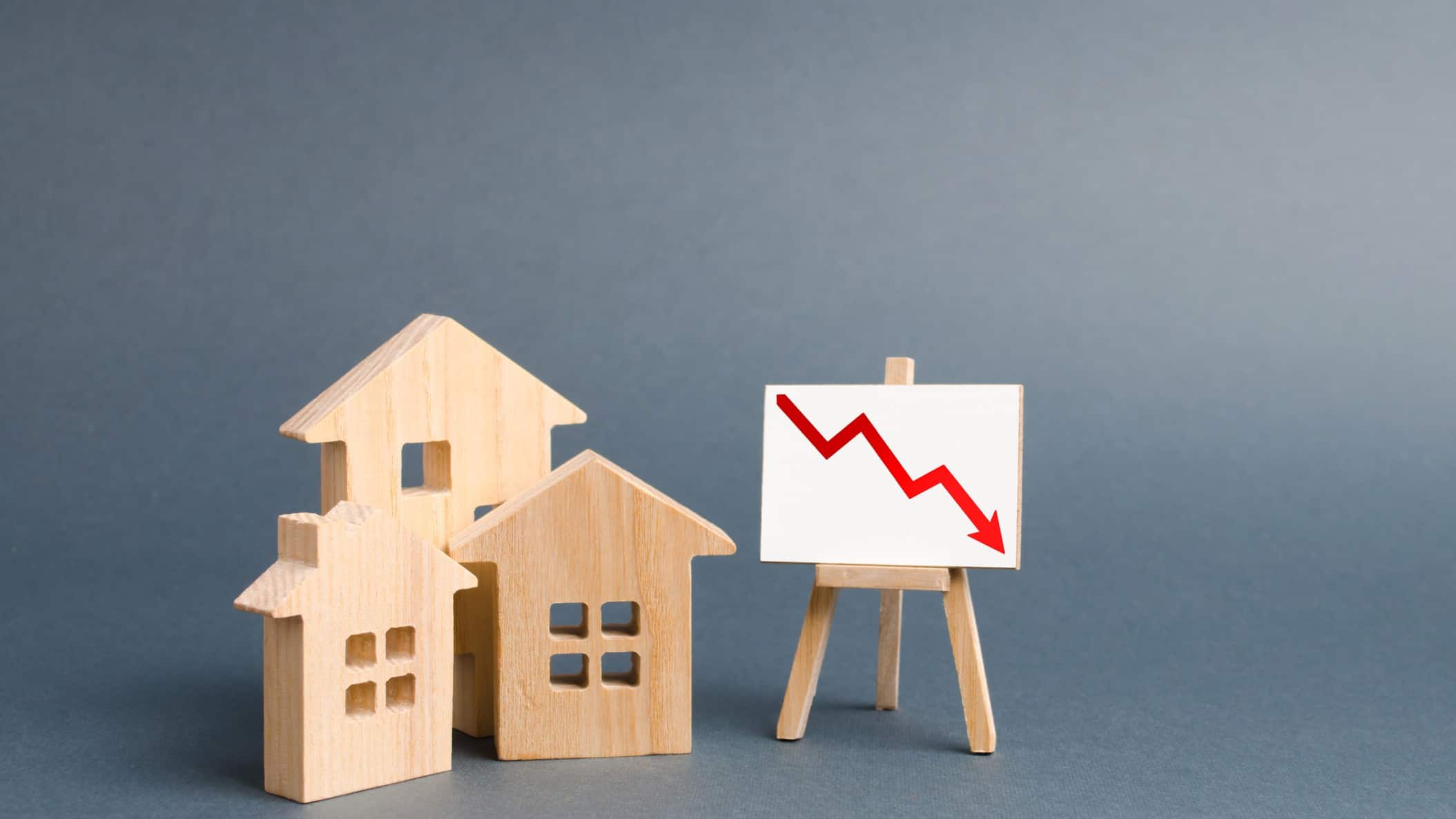 Red arrow on a stand going down with wooden houses next to it.