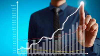 Man pointing an upward line on a bar graph symbolising a rising share price.