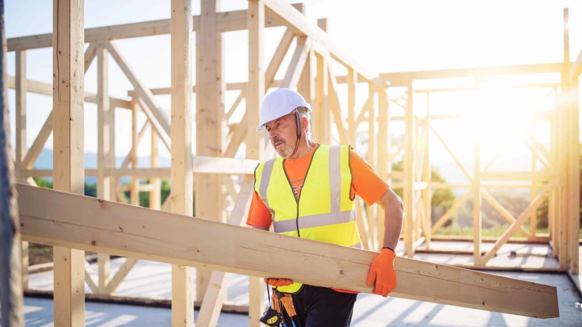 Builder holding long rectangular wood.