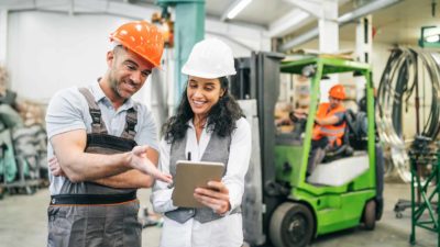Two happy construction workers discussing share price performance with each other.