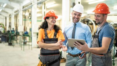 Two happy construction workers discussing the share price with a professionals.