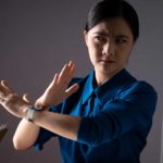 Woman in an office crosses her arms in front of her in a stop gesture.