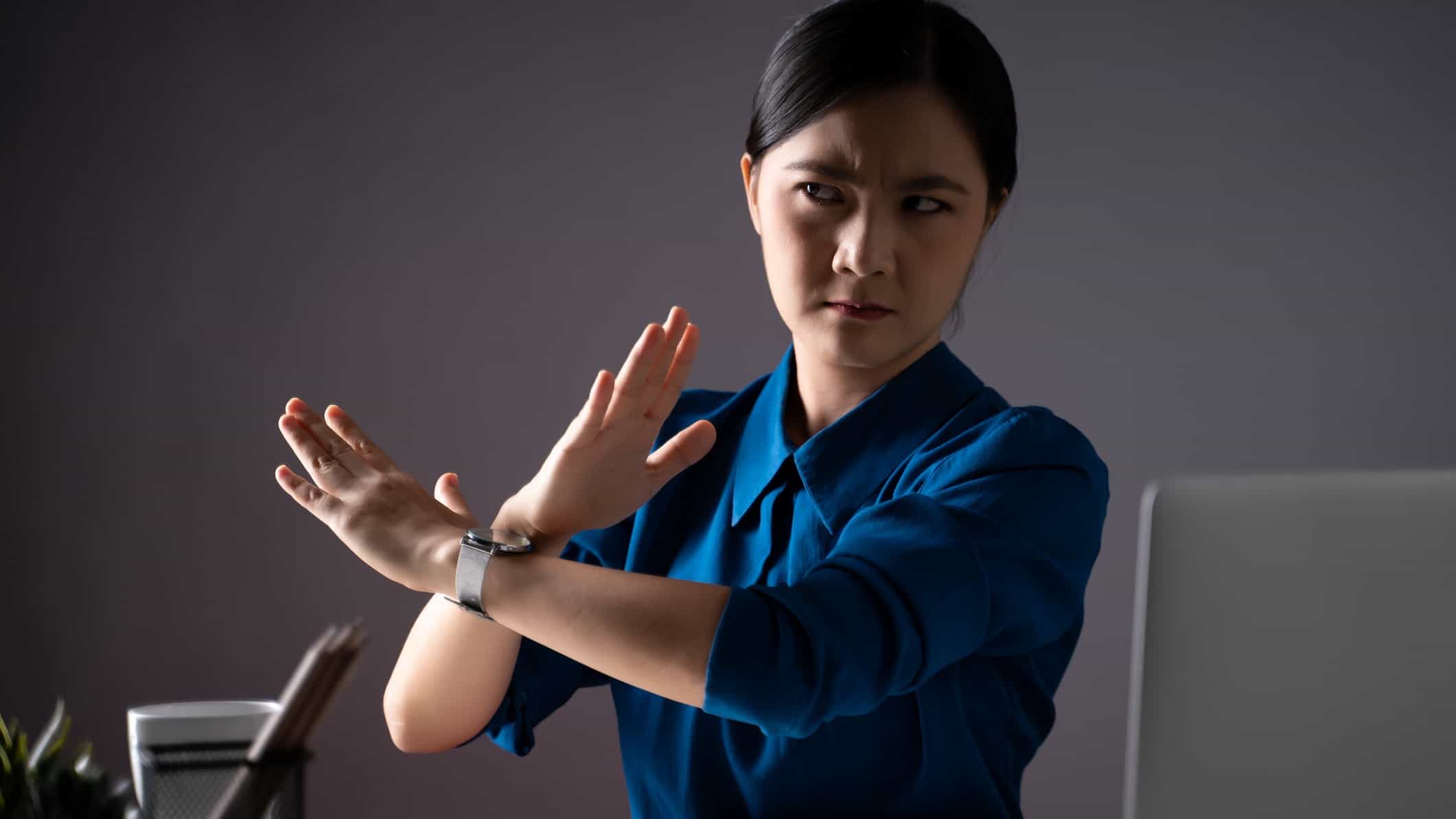 Woman in an office crosses her arms in front of her in a stop gesture.