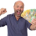 Happy man holding Australian dollar notes, representing dividends.