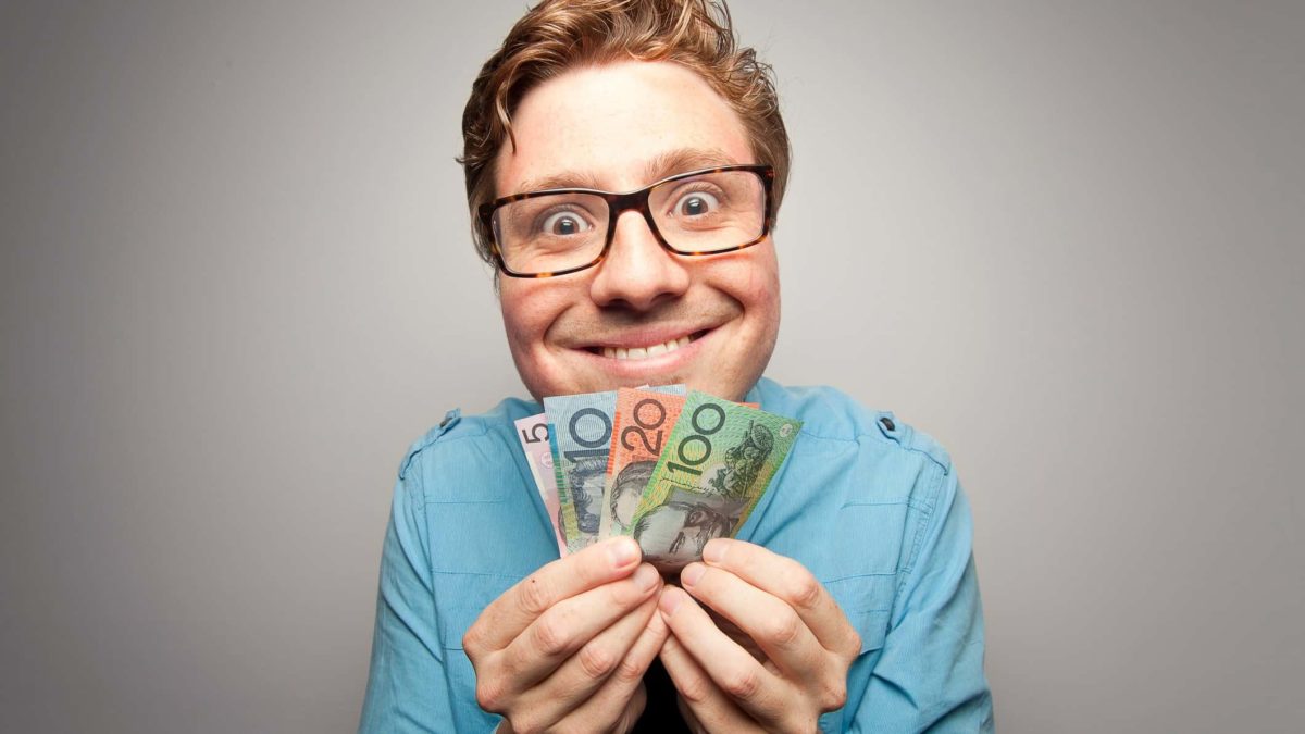 Smiling man holding Australian dollar notes, symbolising dividends.