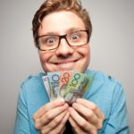 Smiling man holding Australian dollar notes, symbolising dividends.