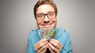 Smiling man holding Australian dollar notes, symbolising dividends.