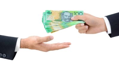 One hand giving $100 notes to another hand, symbolising ex-dividend date.