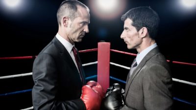 Two men in suits face off against each other in a boing ring.