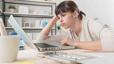 Bored woman working on her laptop.