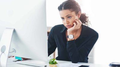 A bored woman looking at her computer, it's bad news.