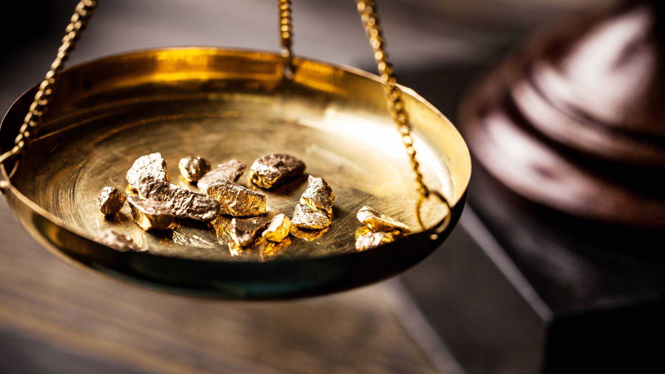 A few gold nullets sit on an old-fashioned gold scale representing ASX gold shares