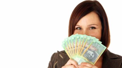 A female CSL investor looking happy holds a big fan of Australian cash notes in her hand representing strong dividends being paid to her
