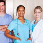 Three healthcare workers standing together and smiling.