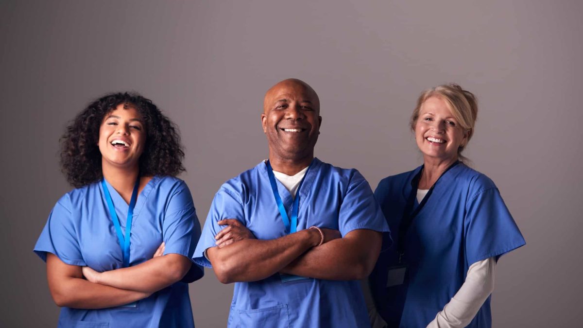 Three healthcare workers standing together and smiling.
