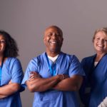 Three healthcare workers standing together and smiling.
