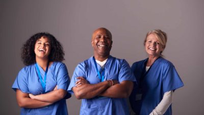 Three healthcare workers standing together and smiling.
