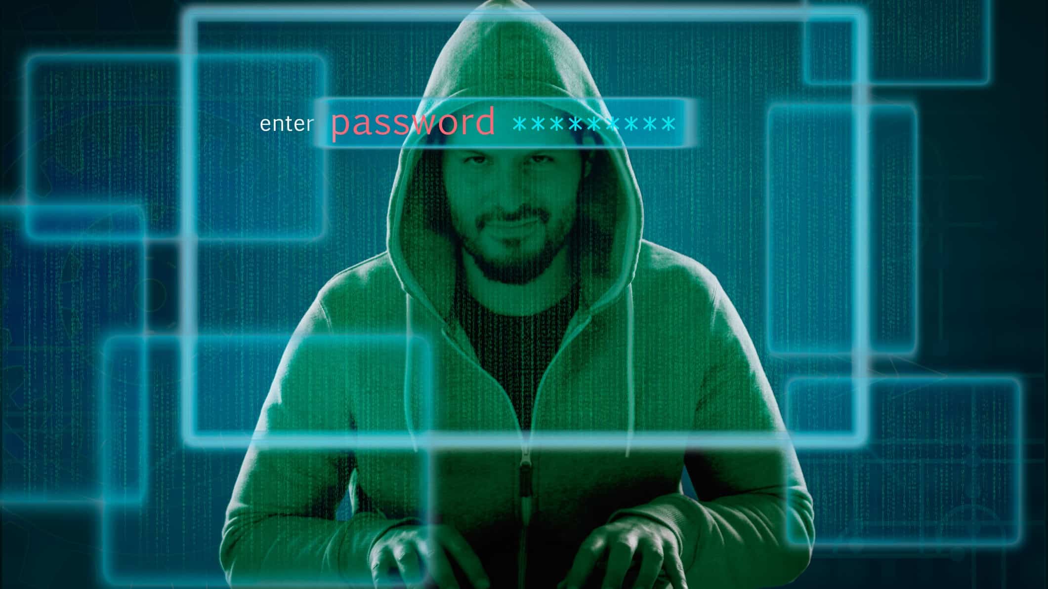 a man in a hoodie grins slyly as he sits with his hands poised on a keyboard. He is superimposed with a graphic image of a computer screen asking for a password, suggesting he is a hacker.