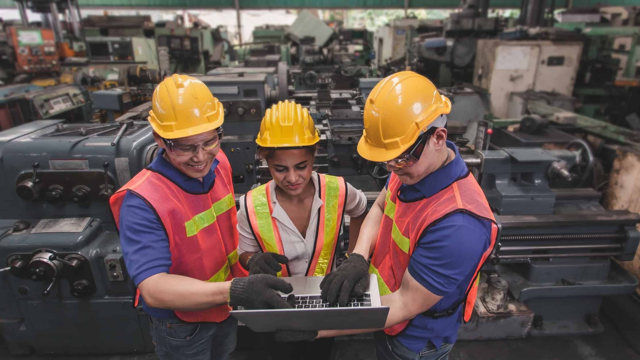 Three happy industrial engineers analysing the share price.