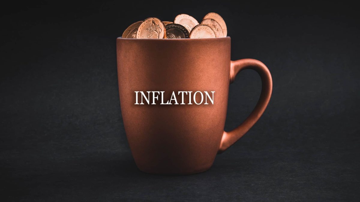 Inflation written on a coffee mug with coins in it.
