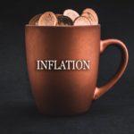 Inflation written on a coffee mug with coins in it.
