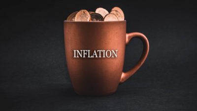Inflation written on a coffee mug with coins in it.