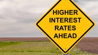 Higher interest rates written on a yellow sign.