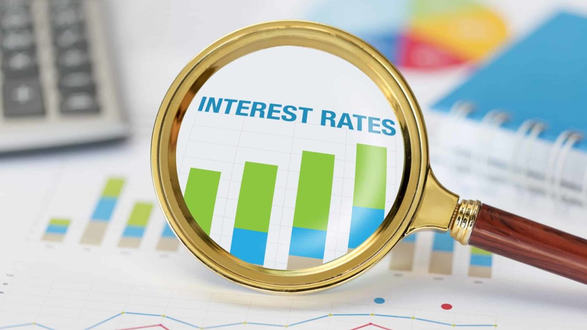 Magnifying glass on a rising interest rate graph.