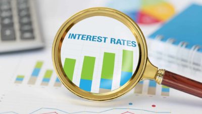 Magnifying glass on a rising interest rate graph.