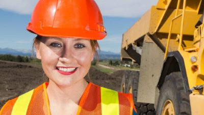 Female miner standing smiling in a mine.