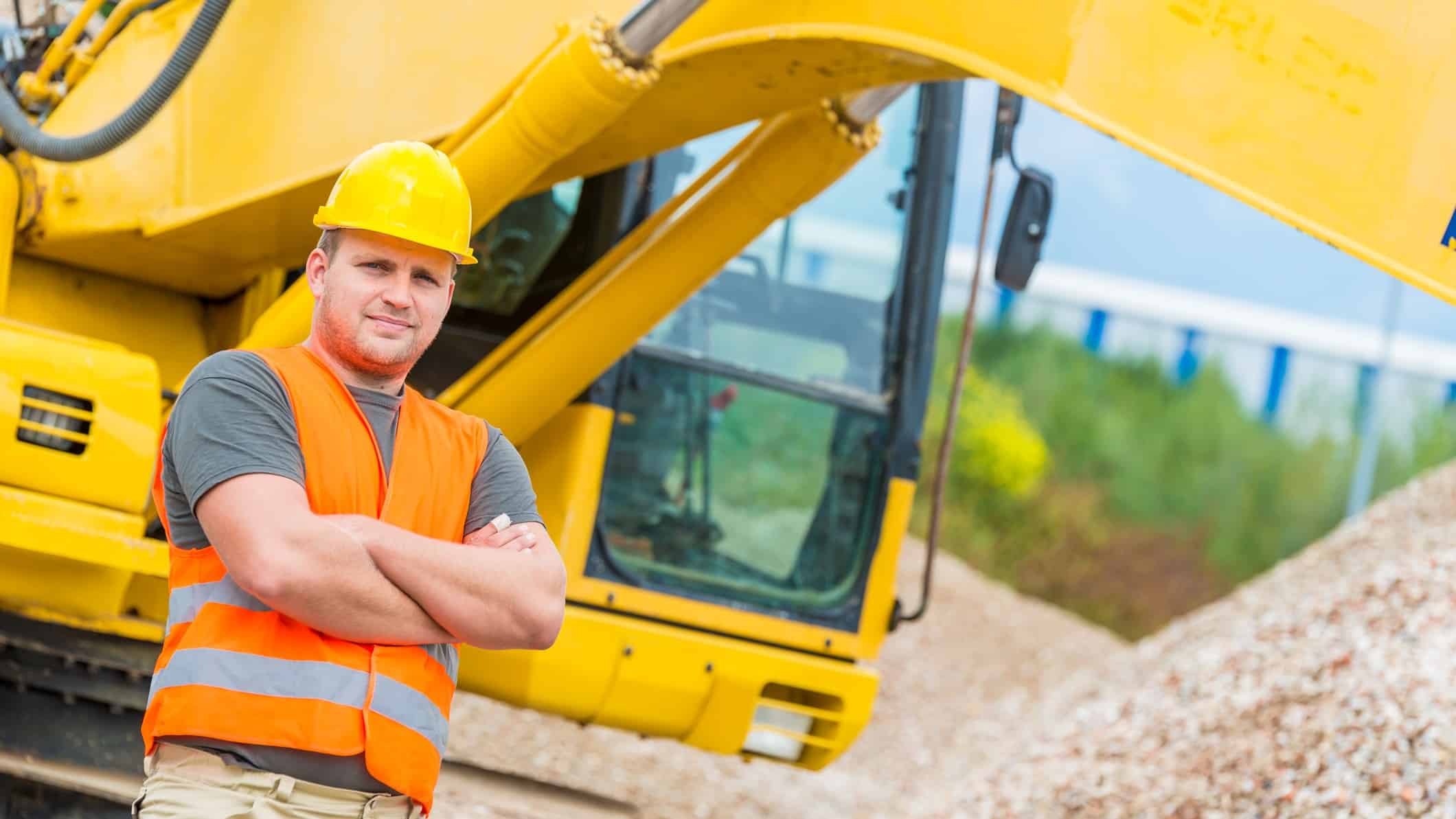 Miner standing in a mine site with his arms crossed.
