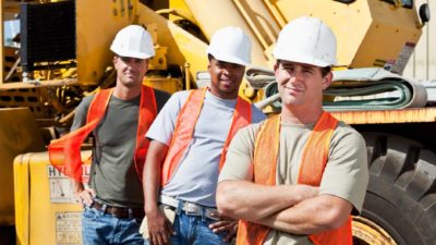 Three miners wearing hard hats and high vis vests take a break on site at a mine as the Fortescue share price drops in FY22