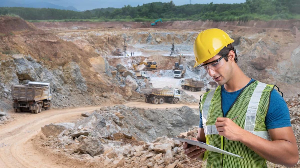 Miner on his tablet next to a mine site.