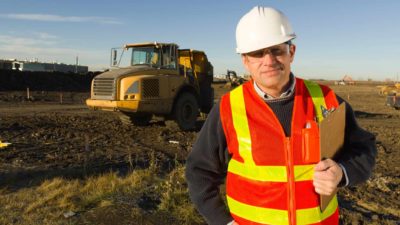 Miner standing in front of a vehicle at a mine site.