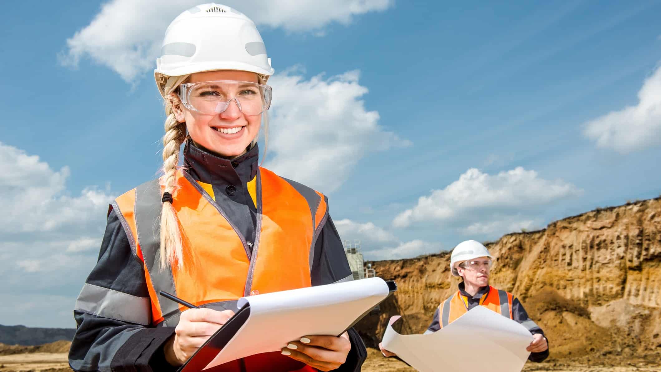 Female miner smiling while inspecting a mine site with another miner.
