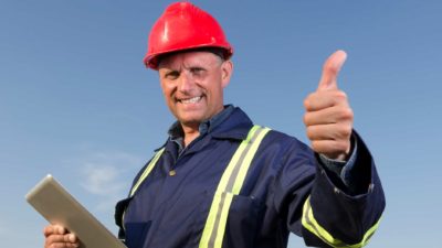 a miner holds his thumb up as he holds a device in his other hand.