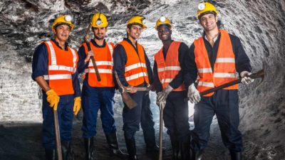 Five happy miners standing next to each other representing ASX coal mining shares which some brokers say could pay big dividends this year