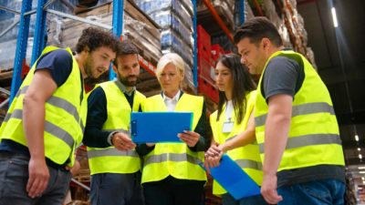 Five workers working on a task in a warehouse.