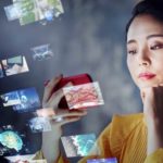 A woman looks at a mobile phone as various screens appear nearby.