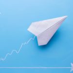 Paper aeroplane rising on a graph, symbolising a rising Corporate Travel Management share price.