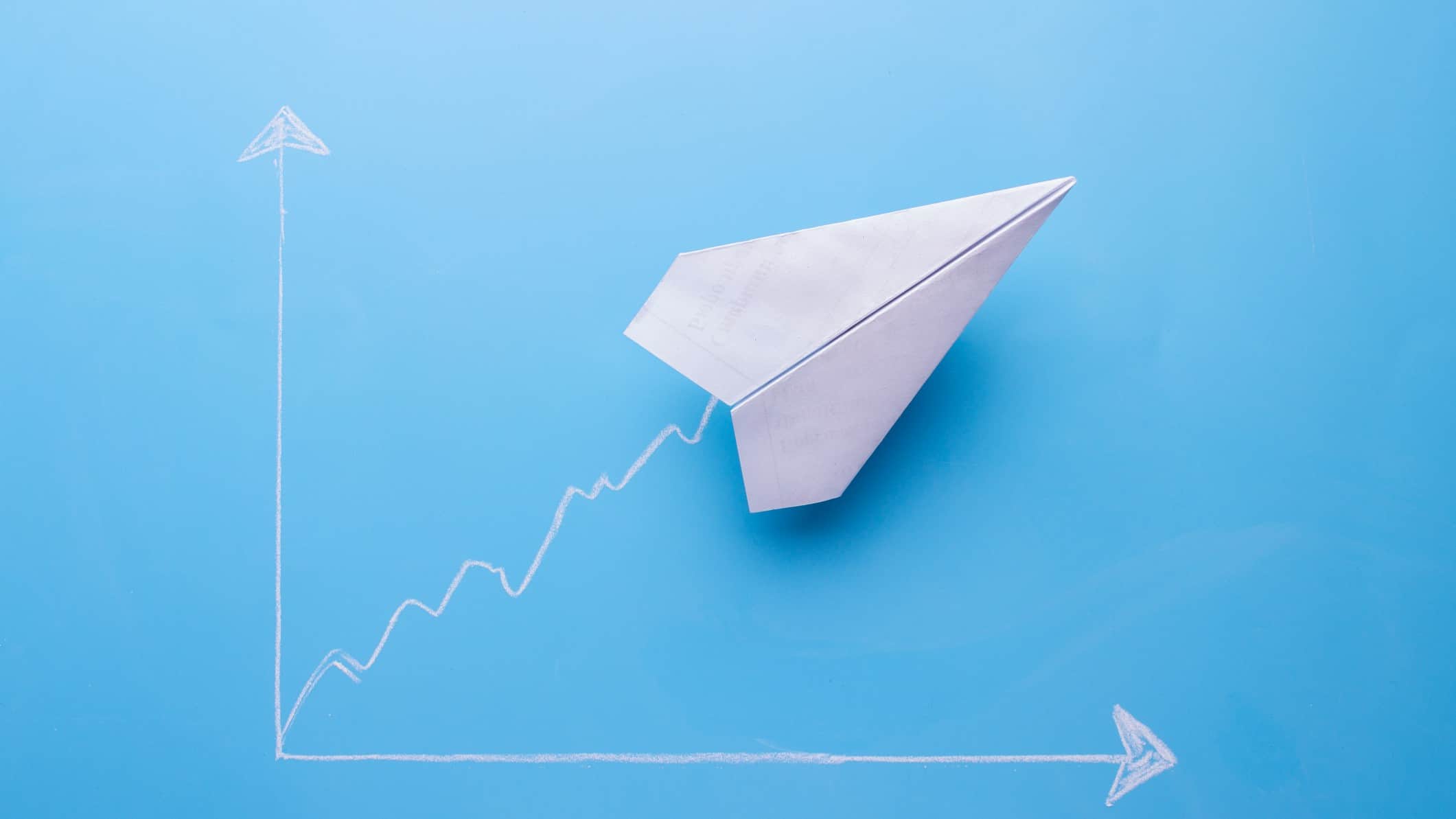 Paper aeroplane rising on a graph, symbolising a rising Corporate Travel Management share price.