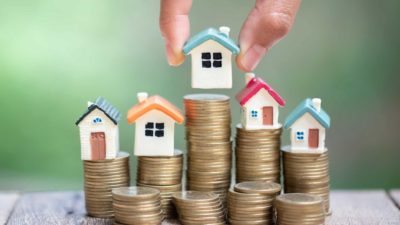 5 mini houses on a pile of coins.