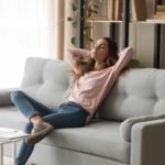 An ASX investor relaxes on her couch as the Harvey Norman share price drops due to the shares trading ex-dividend from today.