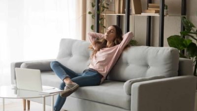 An ASX investor relaxes on her couch as the Harvey Norman share price drops due to the shares trading ex-dividend from today.