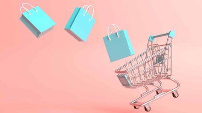 Blue shopping bags falling out of a trolley, symbolising a falling retail share price.