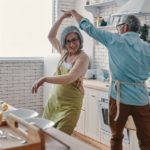 a mature aged couple dance together in their kitchen while they are preparing food in a joyful scene as the Breville share price rises on the back of a 25% profit surge